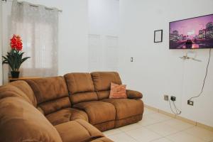un sofá marrón en la sala de estar con TV de pantalla plana en Moderna casa amueblada en residencial privada, en San Miguel