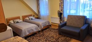 ein Hotelzimmer mit 2 Betten und einem Stuhl in der Unterkunft Hotel Senlīči in Jelgava