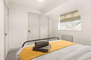 ein Schlafzimmer mit einem Bett mit einer gelben Decke und einem Fenster in der Unterkunft Cotswolds Retreat - Little Corders 