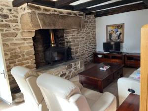 ein Wohnzimmer mit einem Steinkamin und weißen Stühlen in der Unterkunft Longère chaleureuse et familiale - 3 chambres in Limerzel