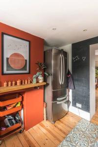 a kitchen with a stainless steel refrigerator and red walls at The Old Post Office - Truly unique, quirky house in Kent