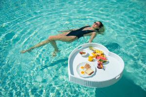 a woman floating in the water next to a table in a pool at Trypiti Resort Blue Dream Palace and Hive Water Park in Limenaria