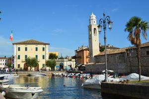 a group of boats in a river with a clock tower at Verbena Holiday Apartment in Lazise