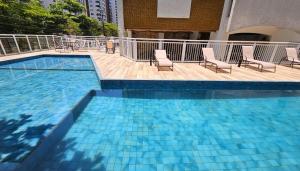 a large swimming pool with chairs and a deck at Ap Moderno - Praia das Pitangueiras - Beach Host in Guarujá