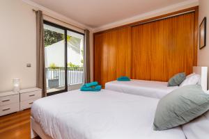 two beds in a bedroom with a window at Villa Nunes, Big Holiday house with private pool in Calheta +57 photos