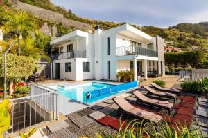 a villa with a swimming pool and lounge chairs at Villa Nunes, Big Holiday house with private pool in Calheta