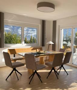 a dining room with a table and chairs and windows at H21 - Modernes Ferienhaus 145qm, 4SZ, Wellnessbereich mit Sauna und Dachterrasse mit Panoramablick, Kühlen und Heizen mit Geothermie in Fügen