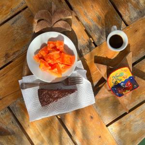 une assiette de fruits et une tasse de café sur une table en bois dans l'établissement Da Fabio, à Negril