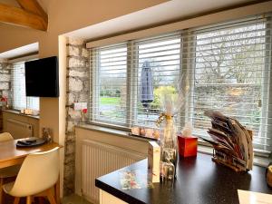 una cocina con mesa y una ventana con persianas en Church Farm Barn Annex, en Somerton