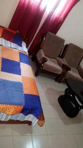 een slaapkamer met een bed en 2 stoelen bij #4 princess self catering apartments, Senegambia area in Sere Kunda