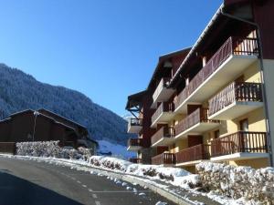 a building with snow on the ground next to a road at Charmant appart rénové 4 pers, balcon sud, plein centre, proche ski et piscine! - FR-1-342-187 in Arêches