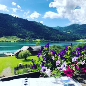 a view of a lake from a balcony with flowers at Ferienhof Hoffmann in Weissensee