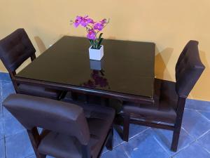 a black dining room table with a vase of flowers on it at Casa Alegria in Cobán