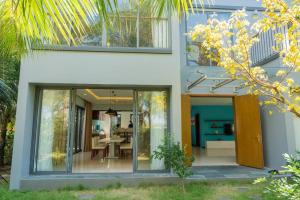 een huis met glazen schuifdeuren en een eetkamer bij 4BR Villa Near The Beach & Shared Pool in Phu Quoc