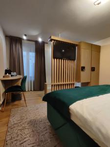 Habitación de hotel con cama, escritorio y TV. en Trend Apart Hotel, en Brasov
