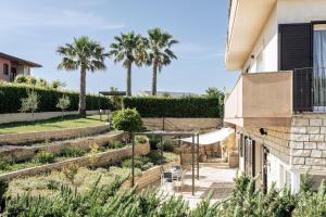 a garden with palm trees and a house at Isula Relax - IsulaTravel in Modica