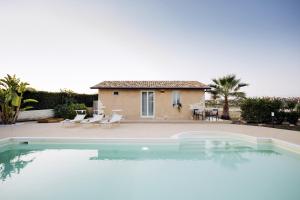 a villa with a swimming pool in front of a house at Isula Relax - IsulaTravel in Modica