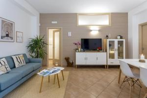 a living room with a blue couch and a tv at Isula Relax - IsulaTravel in Modica