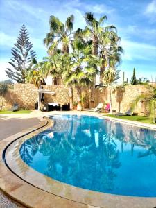 a blue swimming pool with palm trees in the background at Villa targa in Mirleft