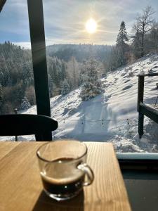 una taza de cristal sentada en una mesa frente a una ventana en Domek w Szczyrku, en Szczyrk