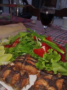 a plate of food with a salad and a glass of wine at Beach and sunset villa in Mboro