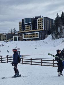 two people on skis in the snow in front of a building at Natural White apartments in Bjelašnica