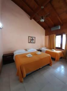 1 Schlafzimmer mit 2 Betten und orangefarbener Bettwäsche in der Unterkunft San Remo Viking Hotel in Pinamar