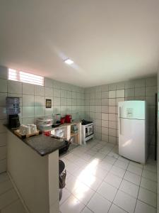 a kitchen with a refrigerator and a tiled wall at Sam Day Suites in Natal