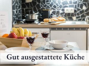 stół z dwoma kieliszkami wina i miską owoców w obiekcie Blumenvilla 6 mit Küche, Balkon, Sauna und Garten w mieście Schneverdingen