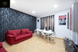 een woonkamer met een rode bank en een tafel bij A Large house in central pieta with BBQ & Terrace by 360 Estates in Tal-Pietà