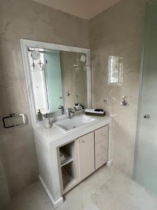 a white bathroom with a sink and a mirror at Spetses maisonette 2 bedrooms for 6 persons. in Spetses