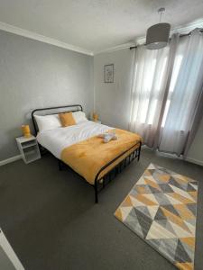 a bedroom with a bed with a yellow blanket on it at Contractor & Family House - Central Grantham in Grantham