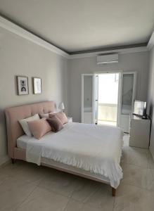 a white bedroom with a large bed with pink pillows at Modern Sea-View Maisonette in Spetses for 6 people in Spetses