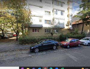 dos autos estacionados en un estacionamiento frente a un edificio en 2 Bedroom Apartment and Separate Kitchen 52mp, en Timisoara