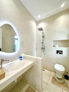 a bathroom with a sink and a toilet and a mirror at L'Amina - Peaceful 1BR Retreat with Cold Jacuzzi in Tangier