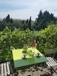Una mesa verde con dos tazas y un jarrón. en La verdine, en Arles
