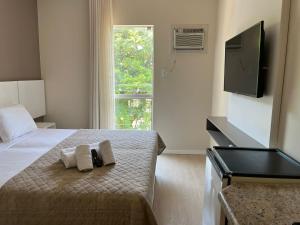 a bedroom with a bed with towels and a flat screen tv at Caravaggio Praia Hotel in Florianópolis +49 photos