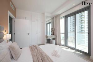 a bedroom with a large white bed with a large window at Luxury 3 Bed Apt with Golf Views in the Greens in Dubai