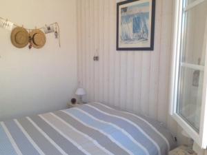1 dormitorio con cama de rayas y ventana en Maison La Brée-les-Bains, 4 pièces, 8 personnes - FR-1-246A-59, en La Brée-les-Bains