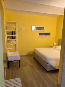 gelbes Zimmer mit einem Bett und einem Stuhl in der Unterkunft Casa Francia Emilia Levante in Bologna