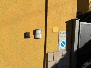 eine gelbe Wand mit zwei Elektroboxen und einem Schild darauf in der Unterkunft Casa Francia Emilia Levante in Bologna