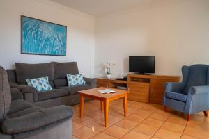 a living room with a couch and a tv at Villas Amarillas in Cala Blanca
