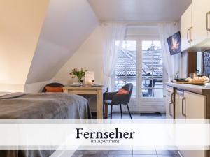 a bedroom with a bed and a desk and a kitchen at Blumenvilla 7 mit Küche, Balkon, Sauna und Garten in Schneverdingen