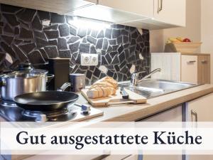 a kitchen with a frying pan on a stove and a sink at Blumenvilla 7 mit Küche, Balkon, Sauna und Garten in Schneverdingen
