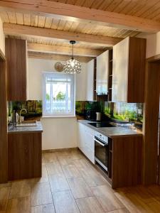 d'une cuisine avec des placards en bois, un évier et une fenêtre. dans l'établissement Domek letniskowy Nad Stawem, à Lipusz