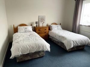 a bedroom with two beds and a dresser and a window at Doolin Getaway. in Lisdoonvarna