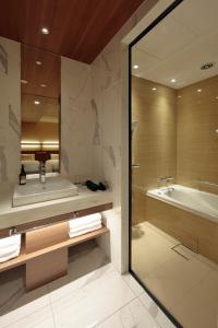 a bathroom with a tub and a sink and a tub and a bath tub at Candeo Hotels Osaka Shinsaibashi in Osaka