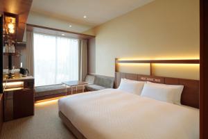 a hotel room with a large bed and a window at Candeo Hotels Osaka Shinsaibashi in Osaka