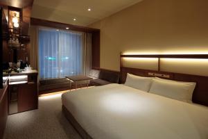 a bedroom with a bed and a sink and a window at Candeo Hotels Osaka Shinsaibashi in Osaka