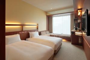 a hotel room with two beds and a television at Candeo Hotels Osaka Shinsaibashi in Osaka